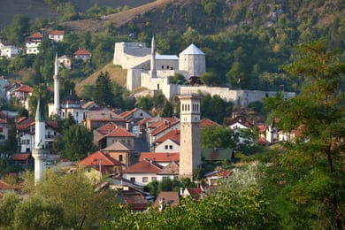 Travnik: tejados rojos, minaretes, torre del reloj y ciudadela en la colina.