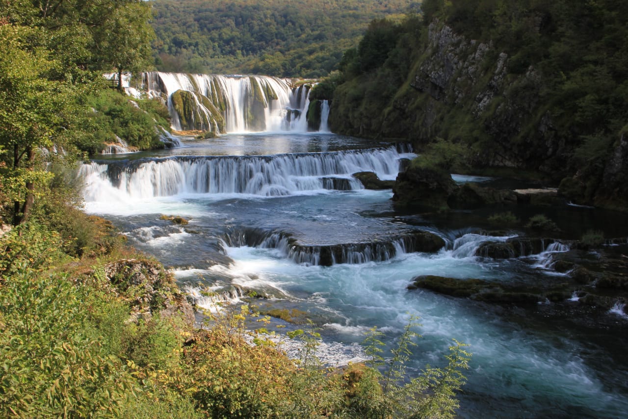 Štrbački buk: las gradas de toba y las cascadas del Una entre acantilados cubiertos de bosque.