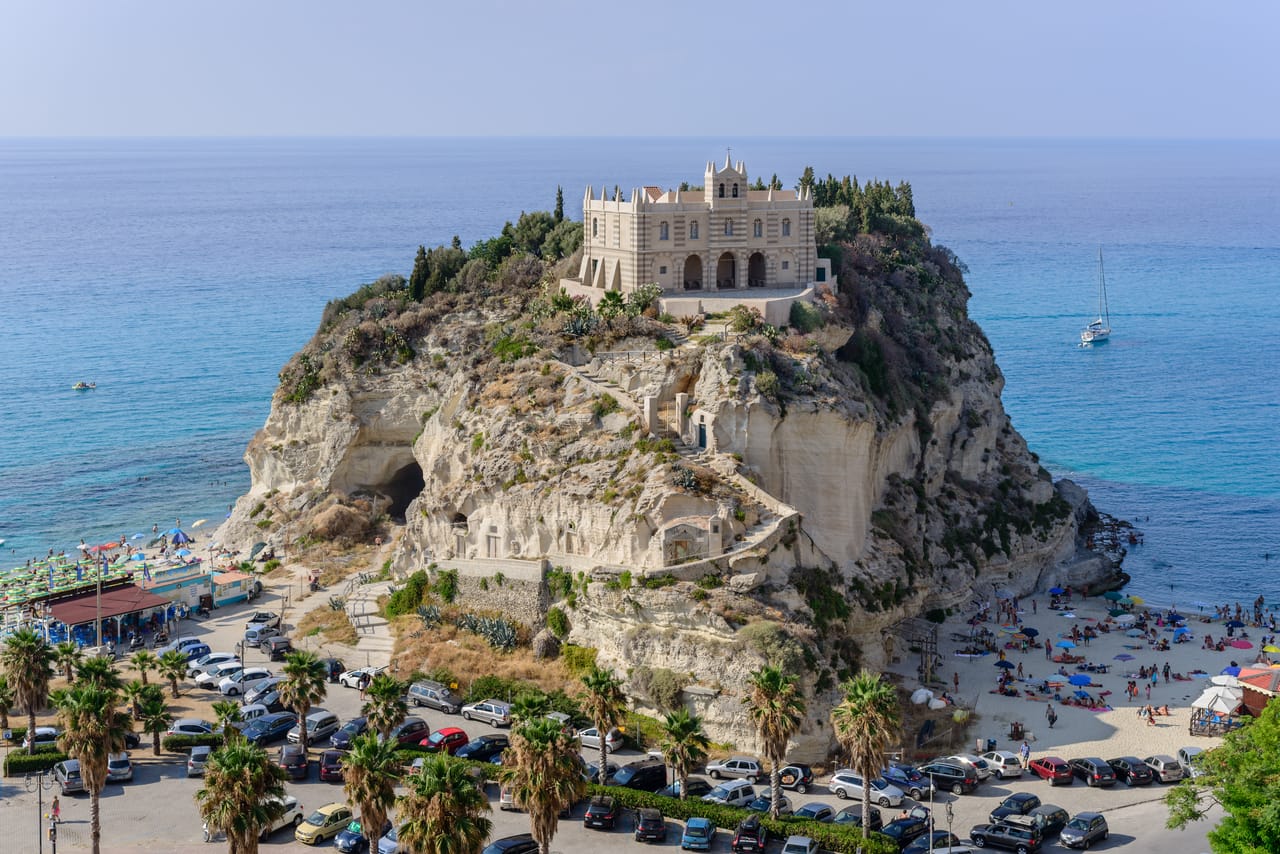 Tropea : le sanctuaire de Santa Maria dell’Isola sur son rocher, au-dessus de la plage et d’une mer turquoise.