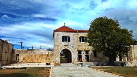 De poort van Maškovića han, in Vrana, onder een weidse blauwe hemel.