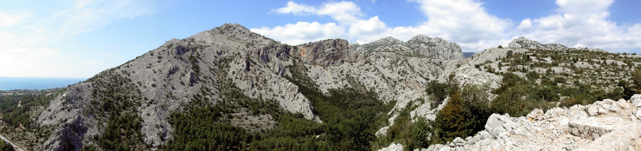 De kalkstenen kammen van Velika Paklenica boven de bossen, onder een blauwe hemel.