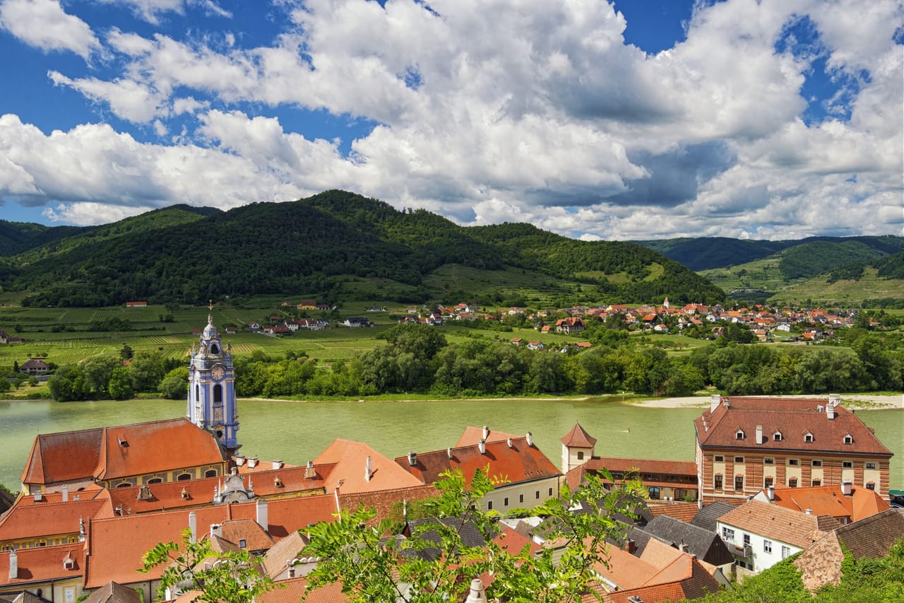 Dürnstein et la tour bleue de son abbaye au bord du Danube, devant les collines de vignes de la Wachau.