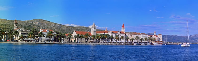 Trogir vu de la mer, ses clochers au-dessus de la riva bordée de palmiers.