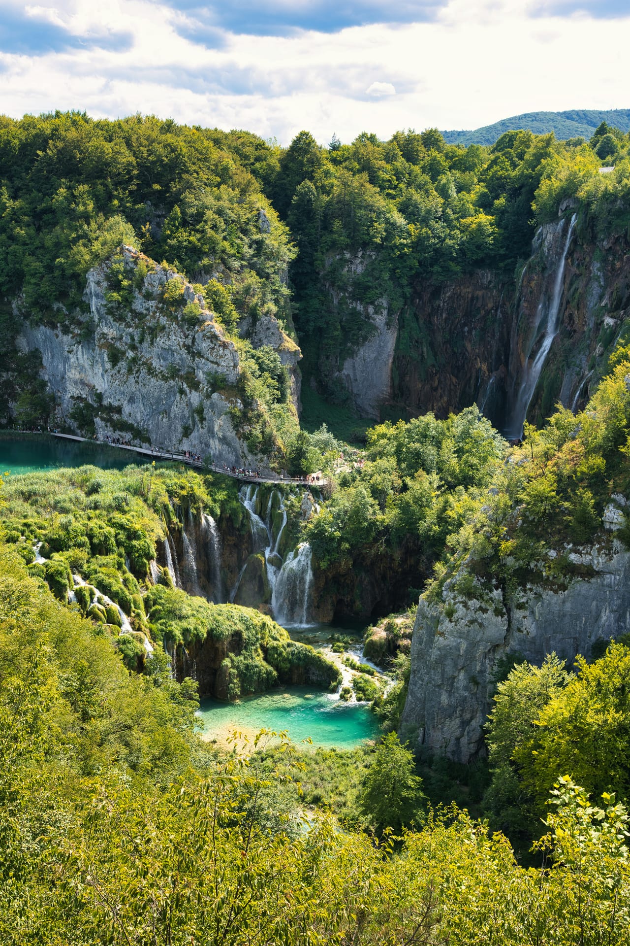 Les lacs de Plitvice, leurs cascades et leurs bassins turquoise entre les falaises boisées.