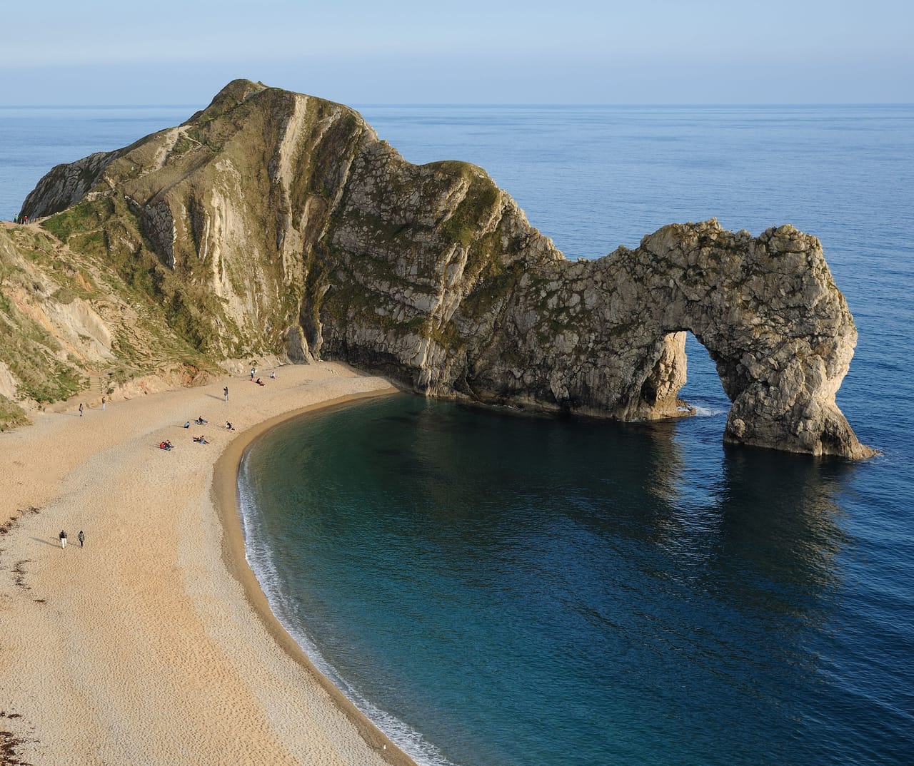 Durdle Door, l’arche de calcaire au bout de sa plage, entre falaises blanches et mer bleue.