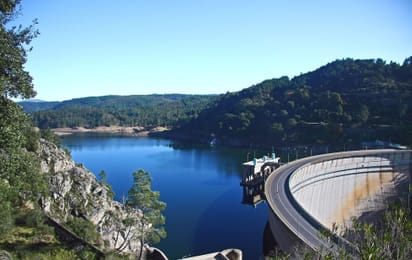 La voûte de béton du barrage du Cabril devant son lac bleu, entre les versants boisés du Zêzere.