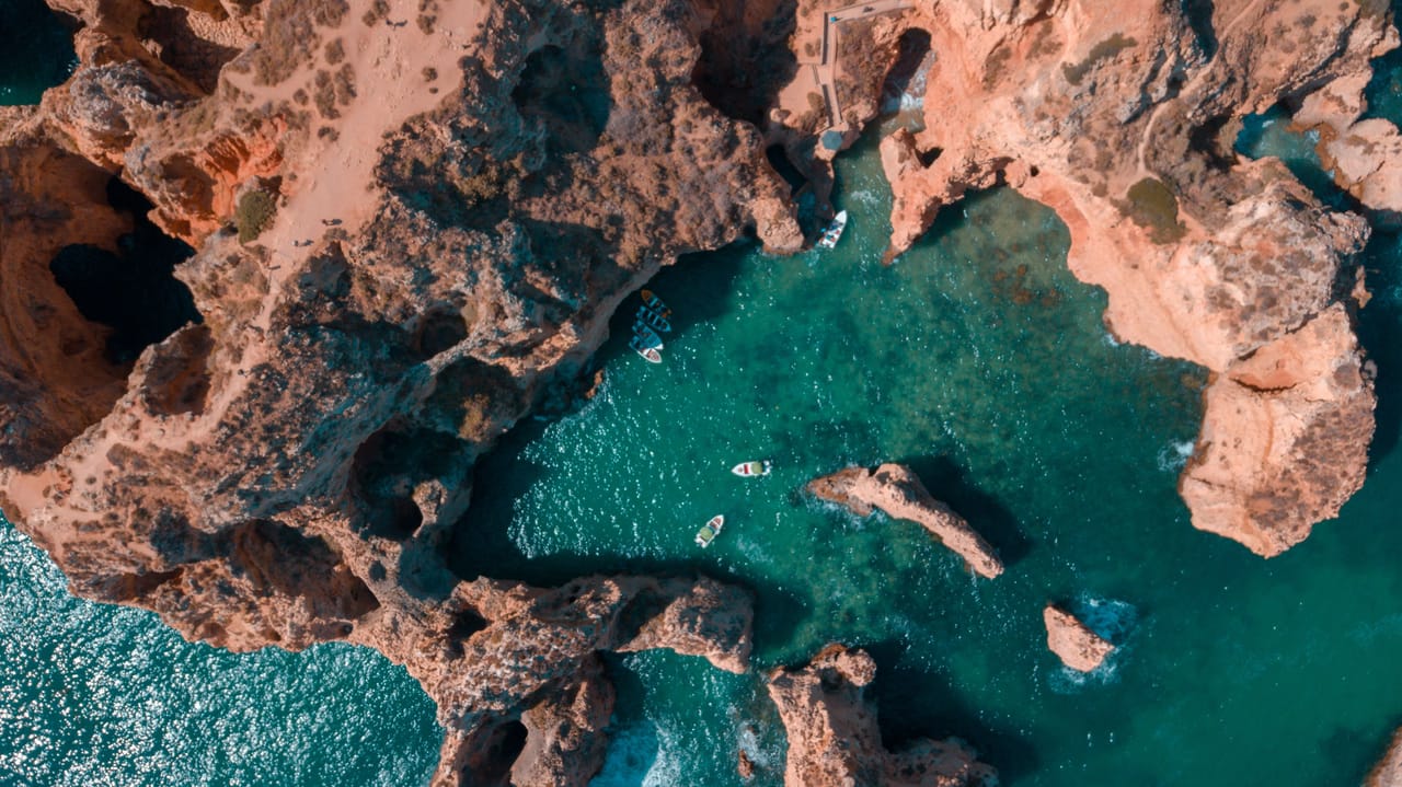 La Ponta da Piedade vue du ciel, près de Lagos : arches de calcaire doré, barques et eau turquoise.