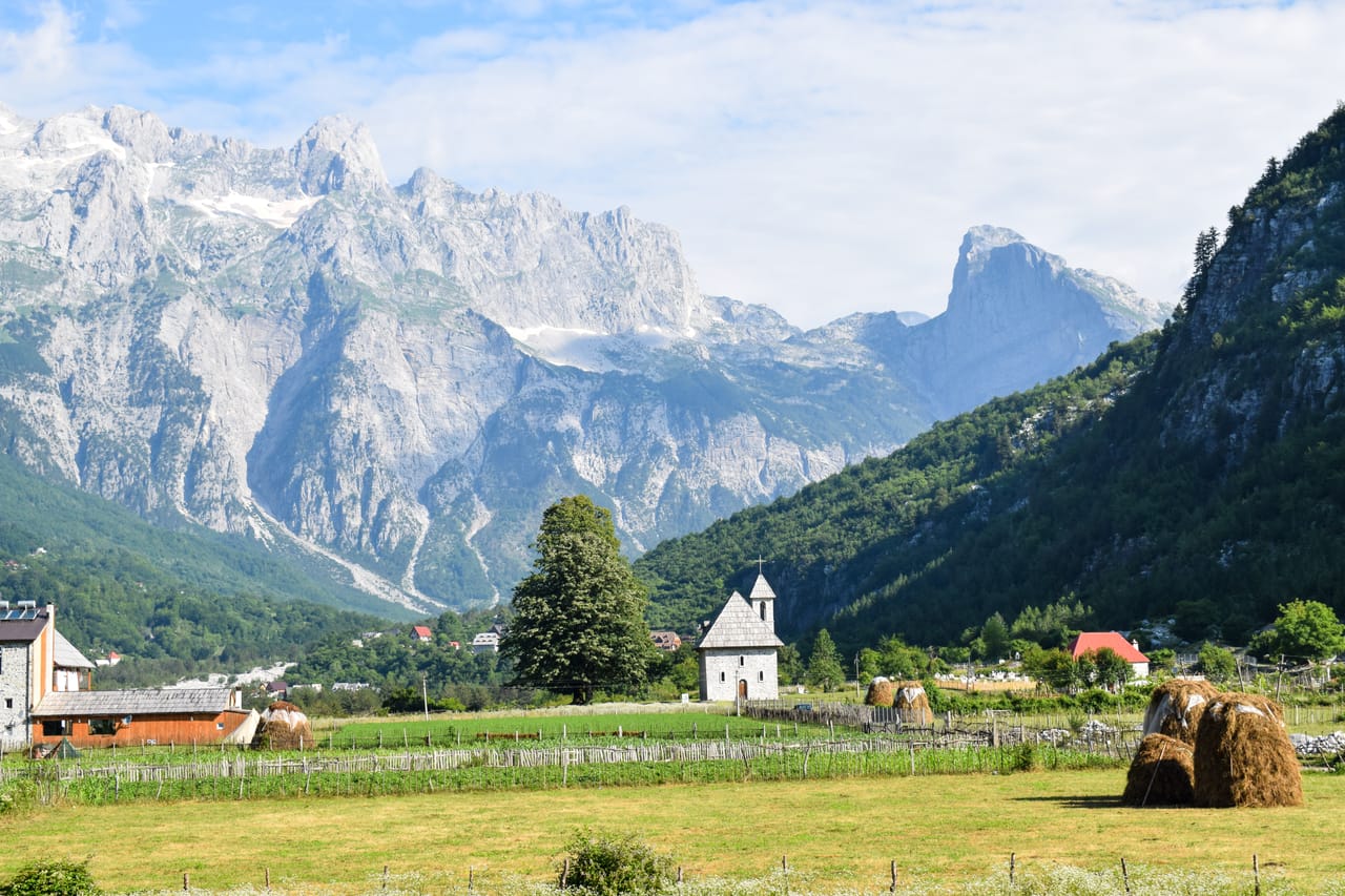L’église de Theth dans les prés, sous les parois calcaires des Alpes albanaises.