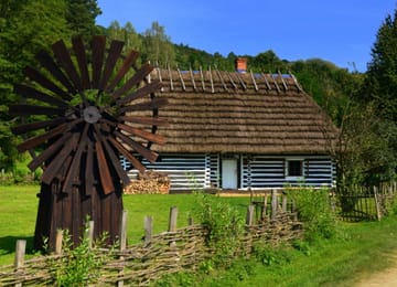 Une chaumière blanchie et un moulin à vent au skansen de Sanok.