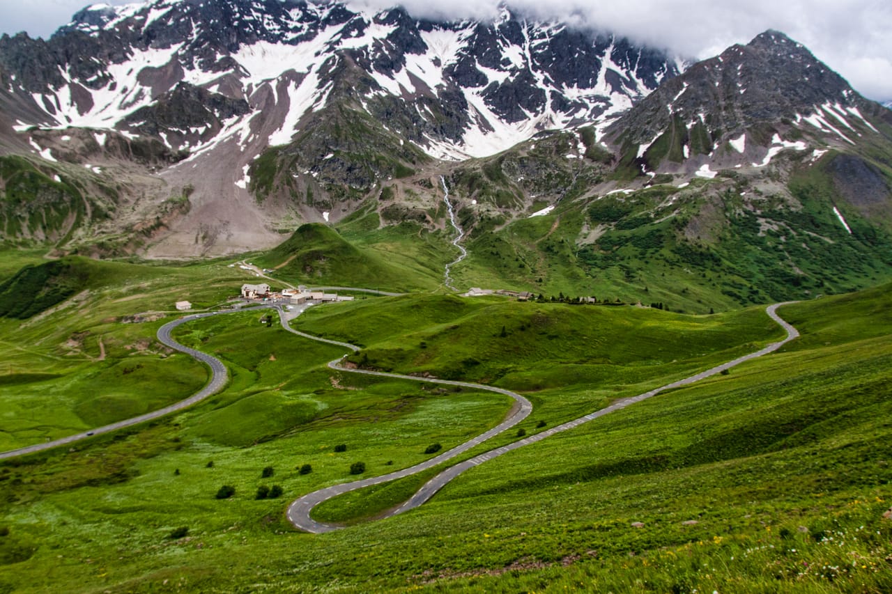 La route du Galibier dans les alpages, sous les sommets enneigés.