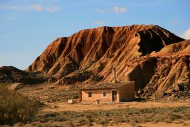 Une cabane au pied d’une butte.