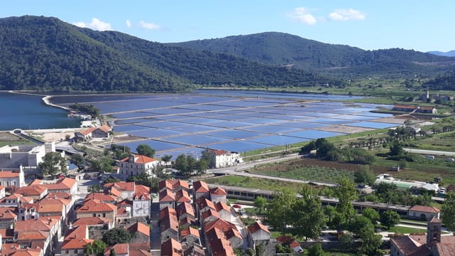 Ston vu des remparts : les toits rouges, les salines et la baie entre les collines.