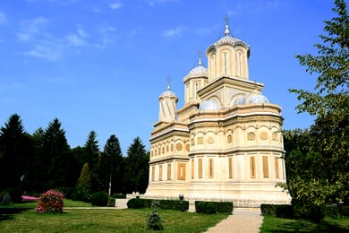 L’église sculptée du monastère de Curtea de Argeș, sous un ciel bleu.