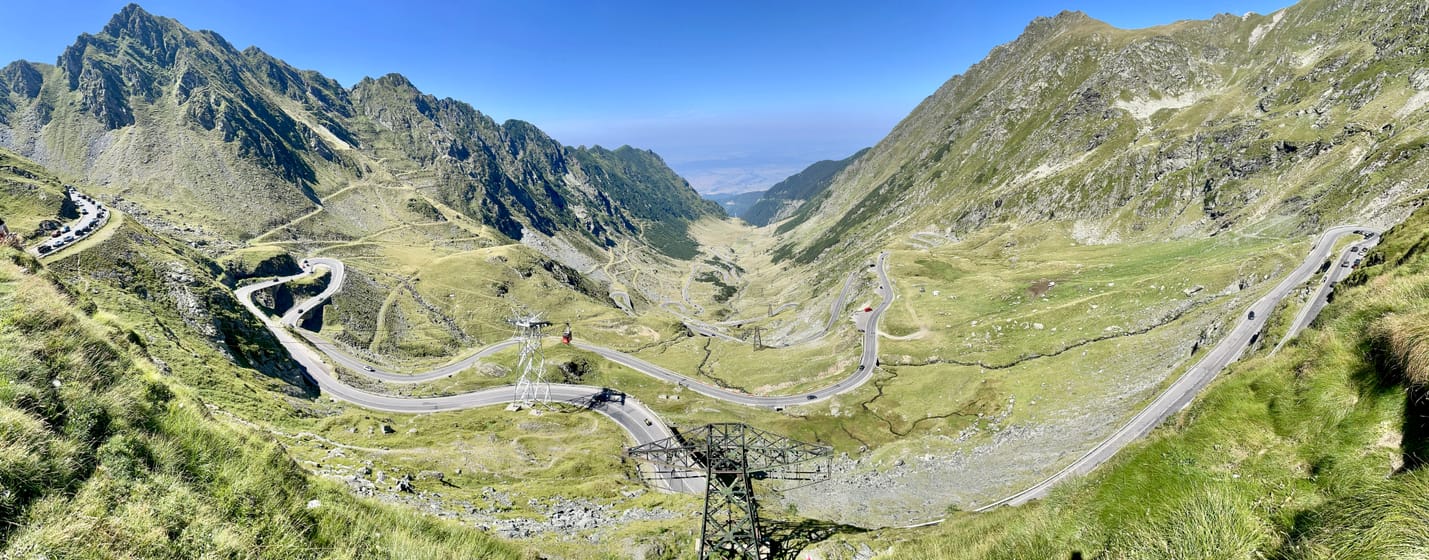 Les lacets de la Transfăgărășan qui montent la vallée glaciaire de Bâlea, sous un ciel bleu.