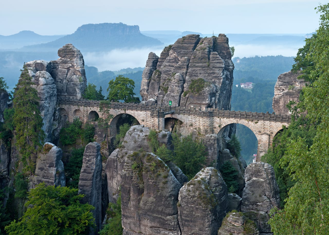 Le pont de la Bastei entre les aiguilles de grès, dans la brume du matin au-dessus de la vallée de l’Elbe.
