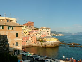 Boccadasse en fin de journée : les maisons colorées sur les rochers et les barques tirées au sec.