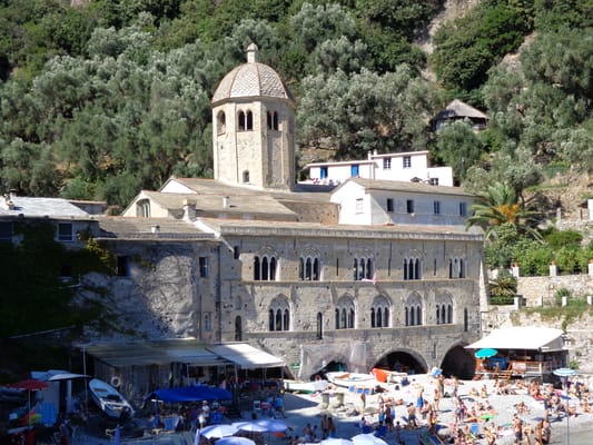 L’abbaye de San Fruttuoso, sa tour octogonale et ses arcades au bord de la plage de galets.