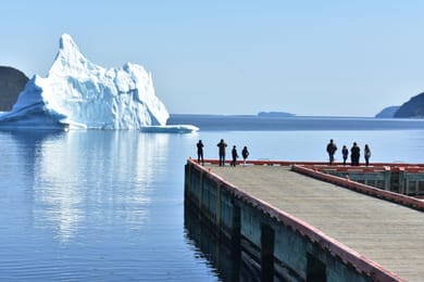 Un iceberg échoué près d’un quai de Terre-Neuve, sous le regard des promeneurs.