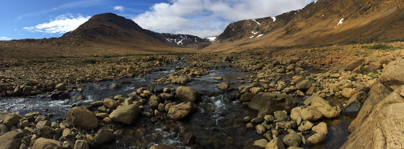 Les Tablelands ocre et un torrent de galets, sous le ciel bleu du Gros-Morne.