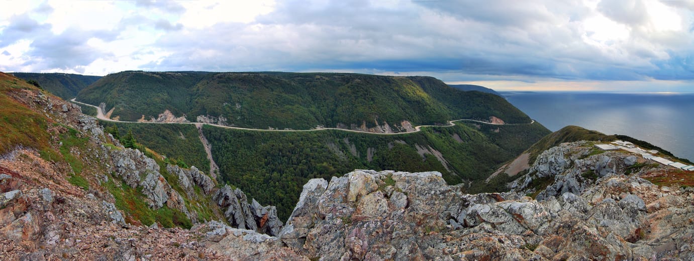 Les lacets de la Cabot Trail entre les collines vertes des Hautes-Terres du Cap-Breton, au-dessus de la mer.