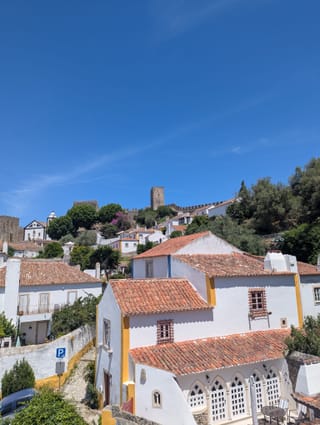 Óbidos : maisons blanches, toits de tuiles et, au-dessus, une tour du château.