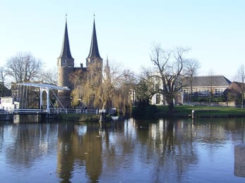 L’Oostpoort de Delft et son pont-levis blanc, reflétés dans le canal.