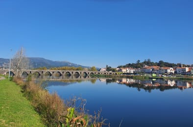 Le vieux pont de Ponte de Lima et le bourg qui se reflètent dans le Lima, par un jour de grand soleil.