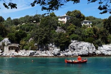Damouchari, son ancienne douane et sa barque rouge au bord de l’eau verte.