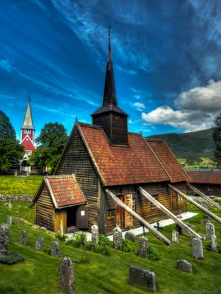 L’église en bois debout de Rødven et ses toits de bardeaux, sous un ciel bleu.