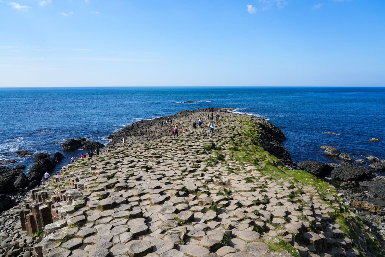 La Chaussée des Géants qui s’avance dans la mer, ses colonnes de basalte sous un ciel bleu.