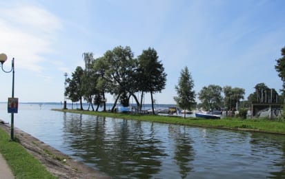 Le canal de Giżycko à son débouché sur le lac Niegocin, bordé d’arbres.
