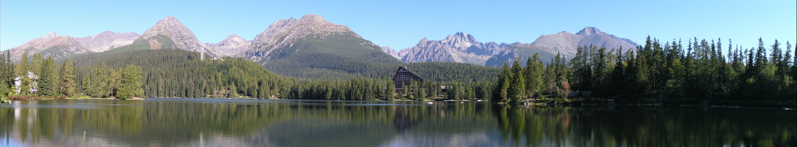 Štrbské pleso par beau temps, avec la crête des Hautes Tatras qui se reflète dans le lac.