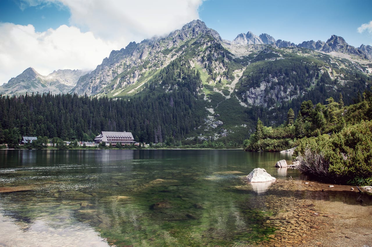 Popradské pleso, son refuge et le cirque de sommets de granit, sous le ciel bleu.
