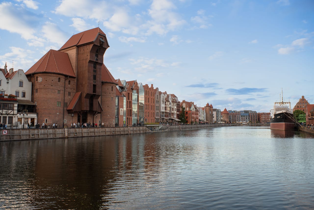 La grue Żuraw et les maisons des quais de la Motława, à Gdańsk, sous le ciel bleu.