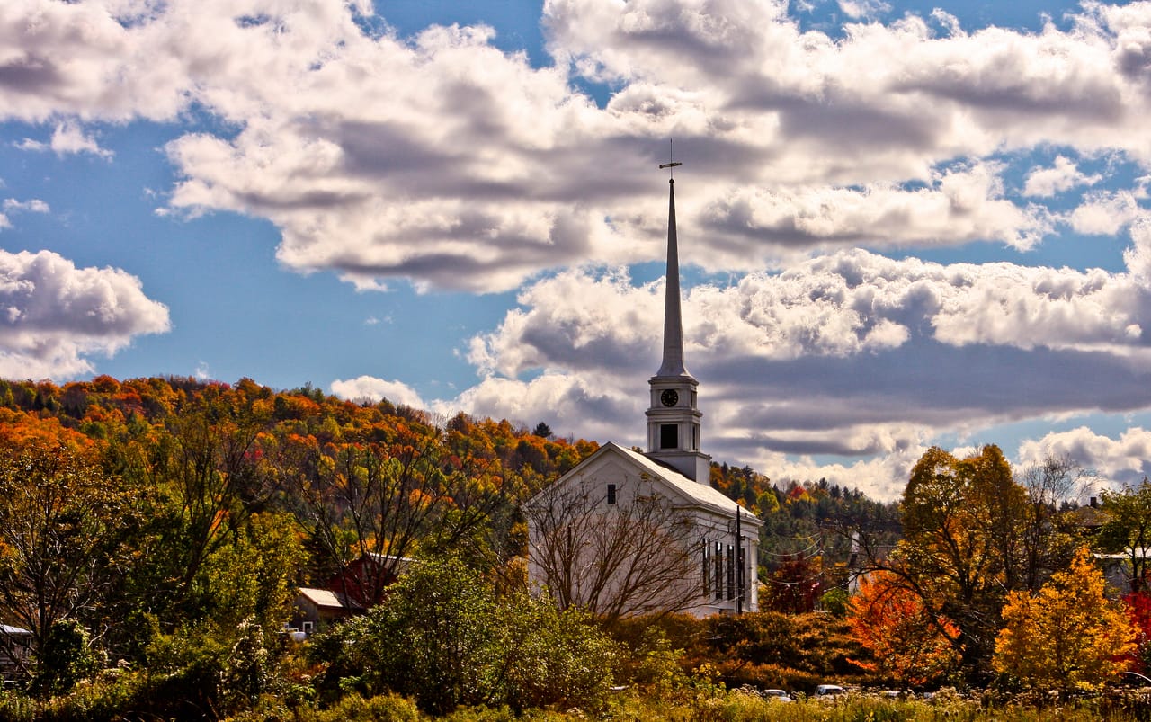 Le clocher blanc de l’église de Stowe devant des collines rousses, en plein été indien.