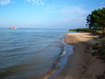 La plage du cap Žirgų et, au loin, le phare de Pervalka sur son îlot.