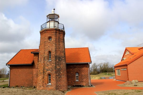 Le phare de brique du cap Ventė et ses maisons aux toits orange.