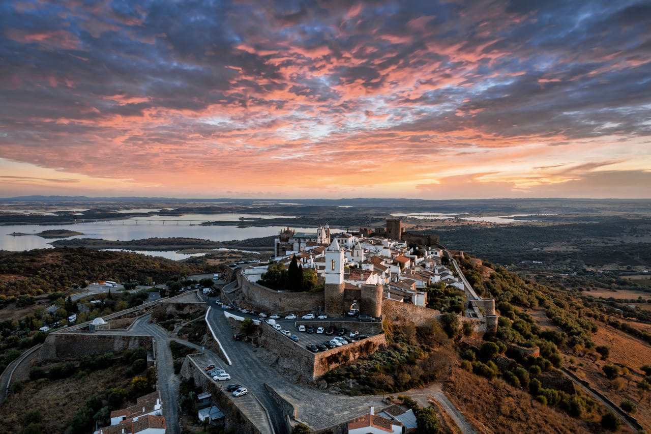 Monsaraz au coucher du soleil : le village blanc dans ses remparts, le donjon et, au loin, le lac d’Alqueva.