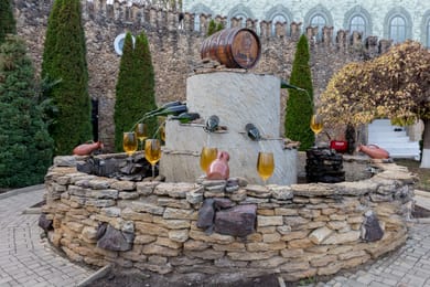 La fontaine aux tonneaux et aux cruches devant le mur crénelé de Mileștii Mici.