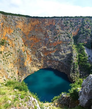 Le lac Rouge d’Imotski au fond de sa doline, entre des falaises ocre.