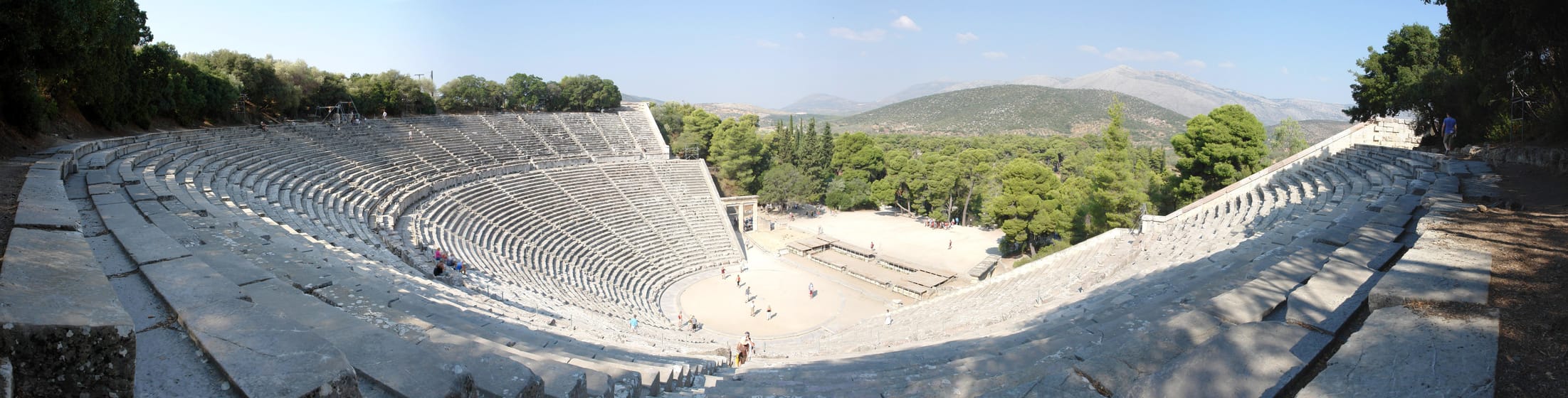 Le théâtre d’Épidaure en plan large, ses gradins dans la pinède et les collines de l’Argolide.