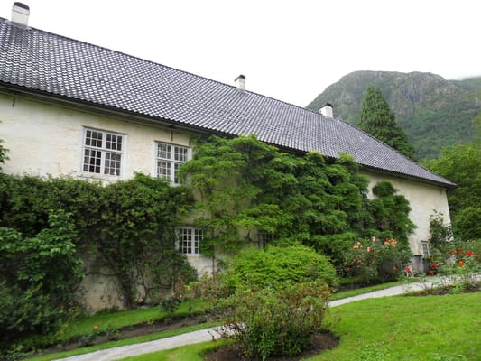Le manoir de Rosendal, sa façade couverte de plantes grimpantes et ses massifs fleuris.