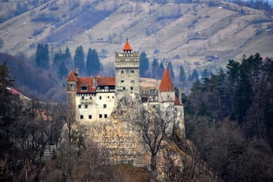 Le château de Bran sur son rocher, devant les collines boisées.