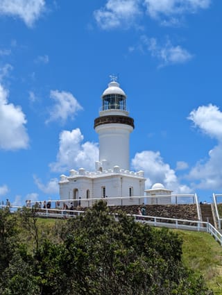 Le phare blanc du cap Byron sous un ciel bleu à nuages.