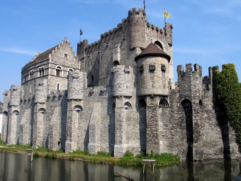 Le Gravensteen de Gand et ses tours crénelées, au bord de l’eau.